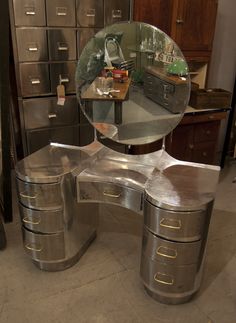 a mirrored vanity with drawers and mirror on it in a room filled with filing cabinets