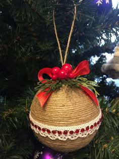 an ornament hanging from a christmas tree decorated with red berries and twine