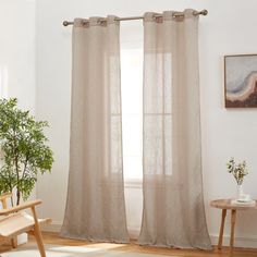 a living room with a chair, table and window curtain in it's corner