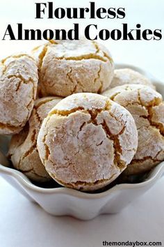 a white bowl filled with powdered sugar cookies on top of a table next to the words flourless almond cookies