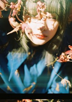 a woman with long black hair and flowers in her hair is looking at the camera