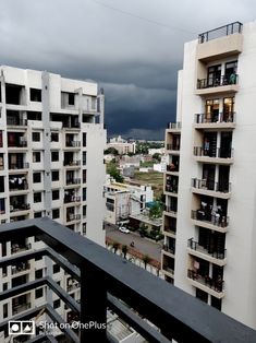 an apartment building with balconies and dark clouds in the sky above it, as seen from a balcony