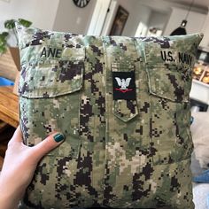 a person holding up a pillow with an army uniform on it