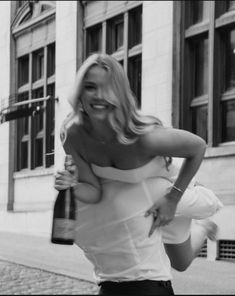 black and white photograph of a woman holding a beer in her right hand while walking down the street