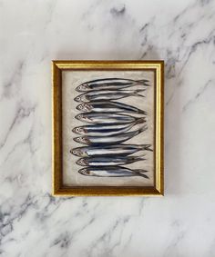 a group of fish sitting on top of a white marble countertop next to a gold frame