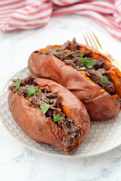 two stuffed sweet potatoes on a plate with a fork and napkin in front of them