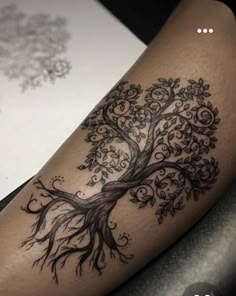 a black and white tree tattoo on the leg