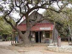 an old wooden building sitting next to a tree