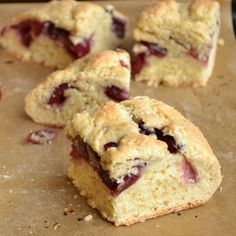 several pieces of scones sitting on top of a piece of parchment paper with cranberry toppings