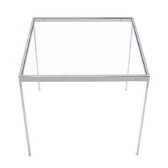 a glass table with metal legs on a white background in front of a white backdrop