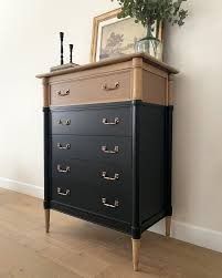 an old dresser with flowers on top in the corner of a room next to a painting