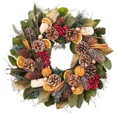 a christmas wreath with oranges, pine cones and other holiday decorations on white background