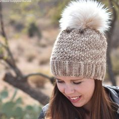 a woman wearing a knitted hat and looking at her cell phone in the desert