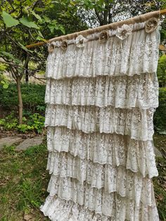 an old lace curtain hanging on a clothes line in front of some trees and bushes