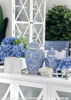 blue and white vases are sitting on a table in front of a china cabinet