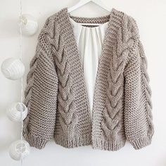 a cardigan sweater hanging on a white wall