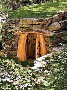 an outhouse in the woods with grass and rocks