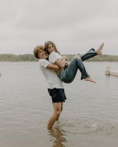 a man holding a woman in his arms while standing in the middle of a lake