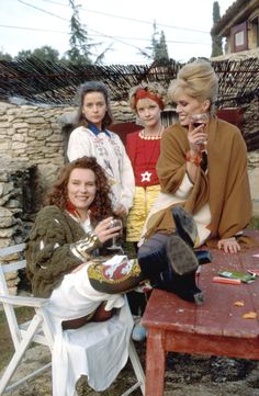 four women sitting around a picnic table talking on the phone