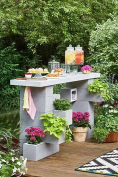 an outdoor table with potted plants and flowers on it in the middle of a garden