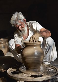 an old man is working on a clay pot