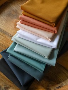 a stack of folded cloths sitting on top of a wooden table next to each other