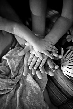 several hands stacked on top of each other in black and white photo with cloth draped around them