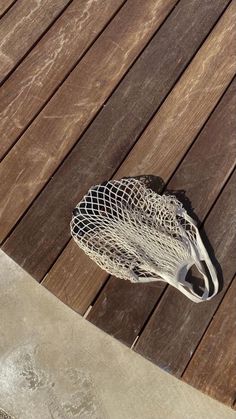 a lacrosse goal sitting on top of a wooden floor next to a tennis racquet