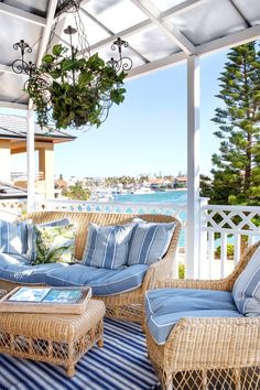 an outdoor living area with wicker furniture and blue striped rugs on the floor