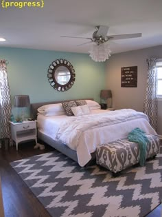 a bedroom with blue walls and white bedding in the center is decorated with gray and aqua accents