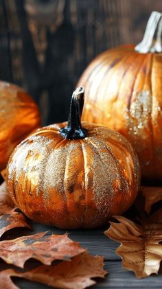 two pumpkins sitting on top of leaves next to each other