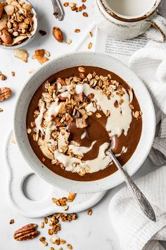 a bowl of chocolate pudding topped with nuts and yogurt next to a cup of coffee