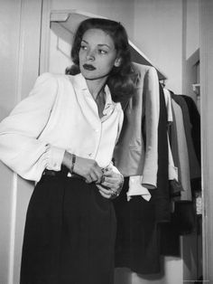 a black and white photo of a woman standing in front of a closet with her hands on her hips