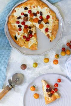 a white plate topped with a pizza next to a slice of pizza on top of a pan