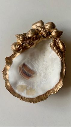 an oyster shell with gold leaf decoration on it's sides and shells in the middle