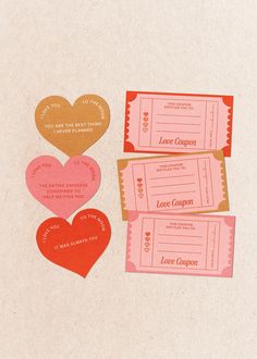 three tickets with hearts on them sitting next to each other