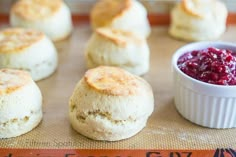 biscuits and cranberry sauce sitting on a baking sheet next to some bread rolls