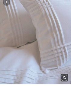 two white pillows sitting next to each other on top of a bed covered in white sheets