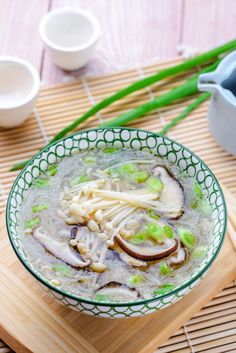 a bowl filled with soup sitting on top of a wooden table next to chopsticks