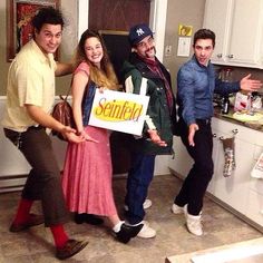 four people standing in a kitchen posing for the camera with a sign that says smile