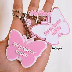 two pink and white butterfly shaped keychains with the words mipimer amio on them