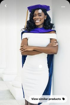 a woman wearing a graduation cap and gown leaning against a wall with her arms crossed