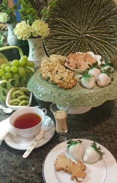 a table topped with plates and cups filled with food next to a vase full of flowers