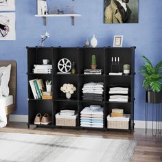 a bedroom with blue walls and white rugs on the floor, an open shelving unit in front of a bed