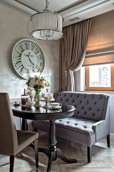 a dining room table with two chairs and a clock on the wall above it,