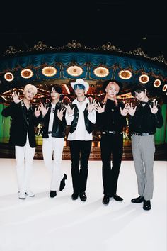 four people standing in front of a carousel with their hands up and one person making the peace sign