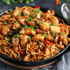 a black plate topped with chicken and noodles