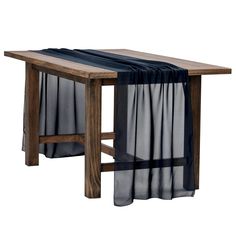 a wooden table with sheer curtains hanging from it's sides, on a white background