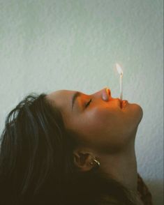 a woman laying down with a lit candle in her mouth