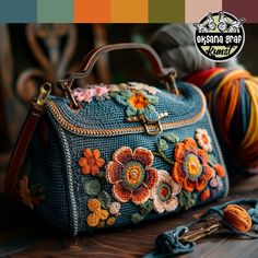 a handbag with flowers on it sitting next to yarn and crochet hooks